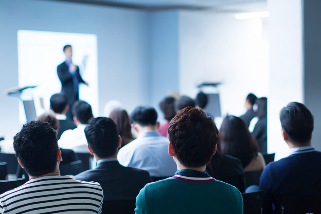 Moderator präsentiert auf der Bühne bei einer Konferenzsitzung.